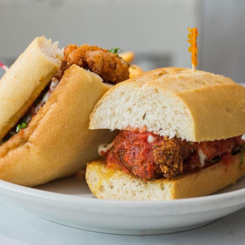 Two delicious-looking sandwiches, one with fried chicken and the other with meatballs and marinara sauce.